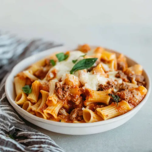 Cheesy rigatoni dish highlighting its vibrant sauce and rustic texture.