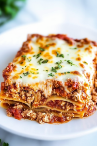 Million Dollar Lasagna plated with parsley garnish, highlighting its creamy layers.