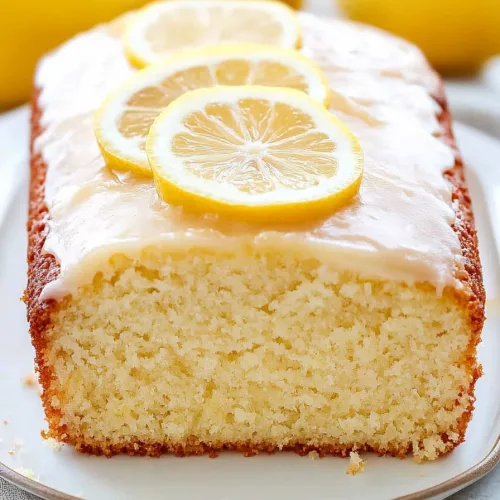 Moist lemon cake on a white plate with whole lemons in background