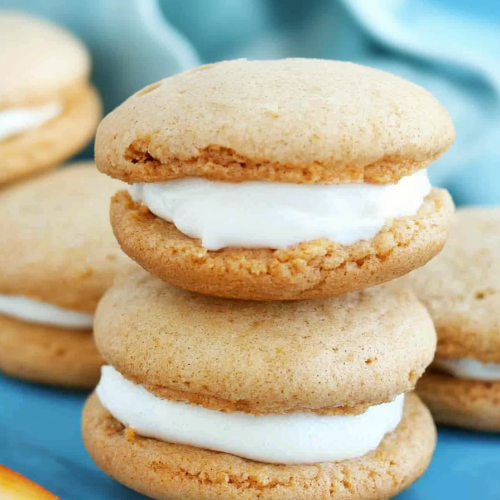 Dessert sandwiches arranged neatly, contrasting warm tones with a cool background.