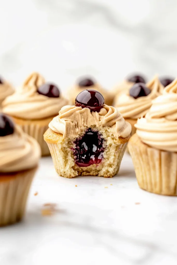 Cupcake with a bite taken out, showing jam filling inside the moist cake.