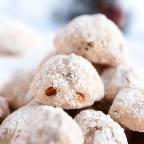 Stack of sugarโcovered cookies showing soft, nutโfilled center