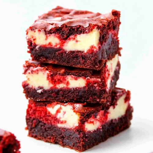 Stacked dessert squares showing red velvet layers with creamy cheesecake center.