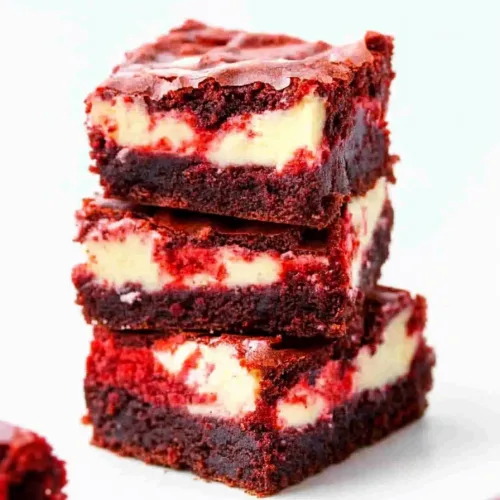 Stacked dessert squares showing red velvet layers with creamy cheesecake center.