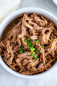 Savory shredded beef with visible fibers and a sprinkle of parsley.