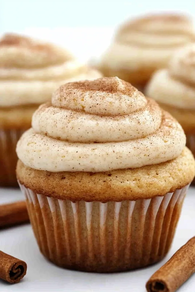 Close-up of a fluffy cupcake topped with creamy cinnamon-speckled frosting.