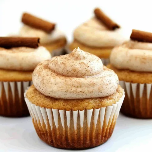 Vanilla cupcake topped with cinnamon frosting and a cinnamon stick garnish.
