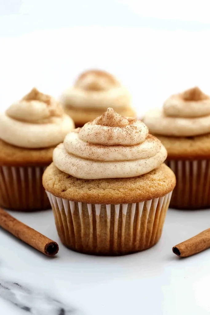 Freshly baked cupcakes decorated with smooth frosting and a dusting of warm spices.
