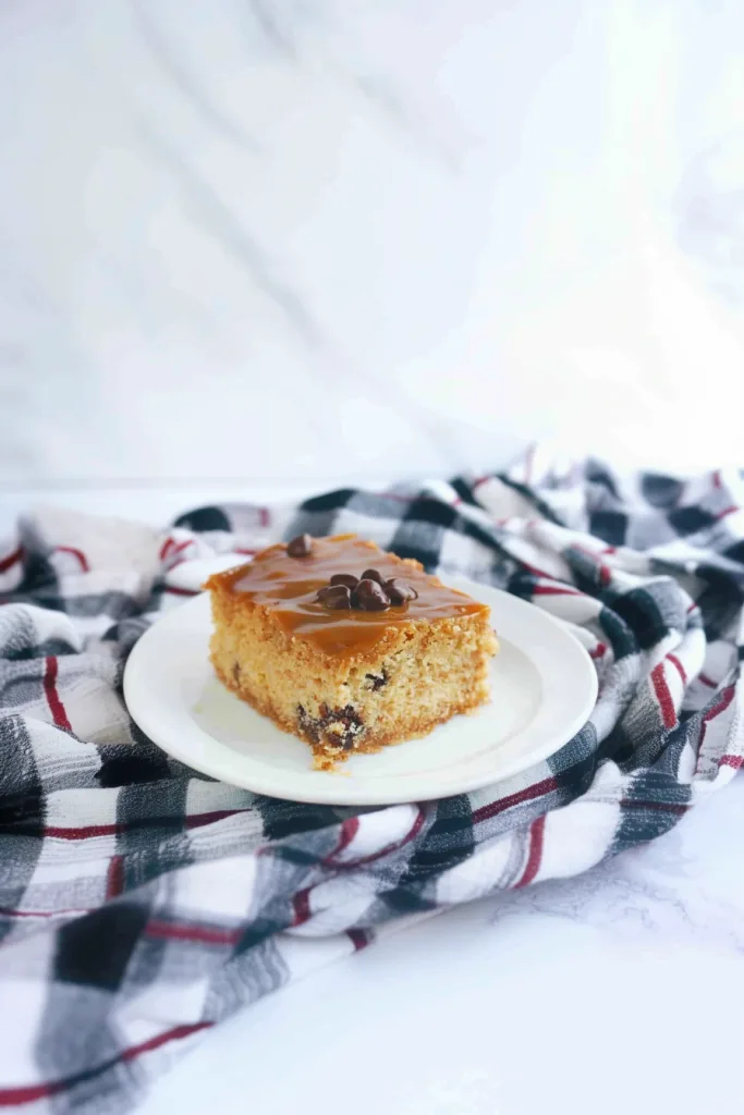 Square slice of golden cake topped with glossy raisins.