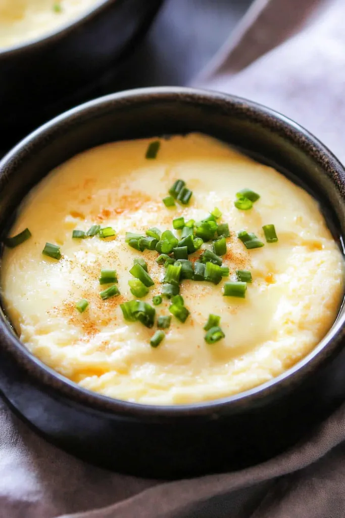 Savory steamed eggs served warm, with paprika dusting and herbs adding color contrast.