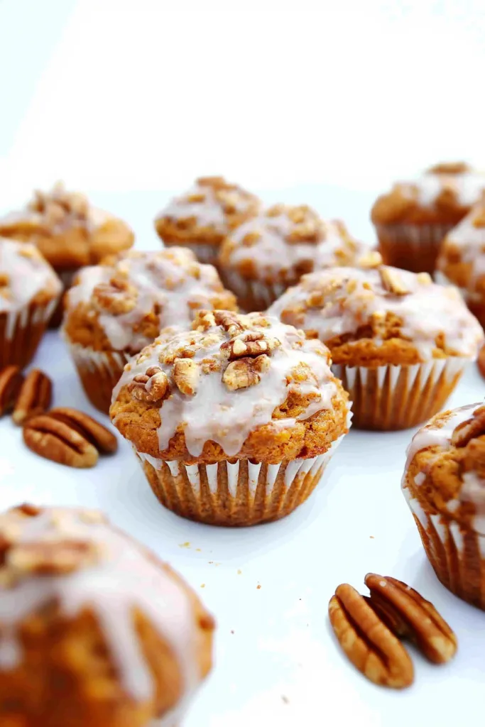 Golden muffin topped with chopped pecans and a drizzle of glaze