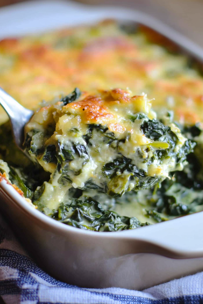 Golden baked casserole with creamy spinach layers lifted by a spoon