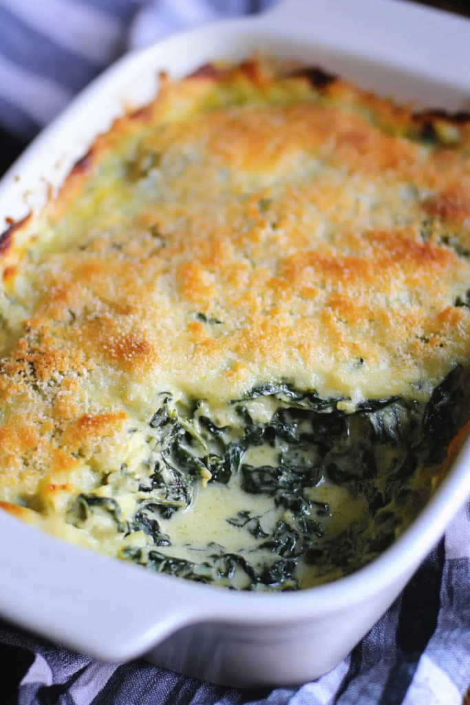 Overhead view of casserole pan with golden crust and green spinach peeking through