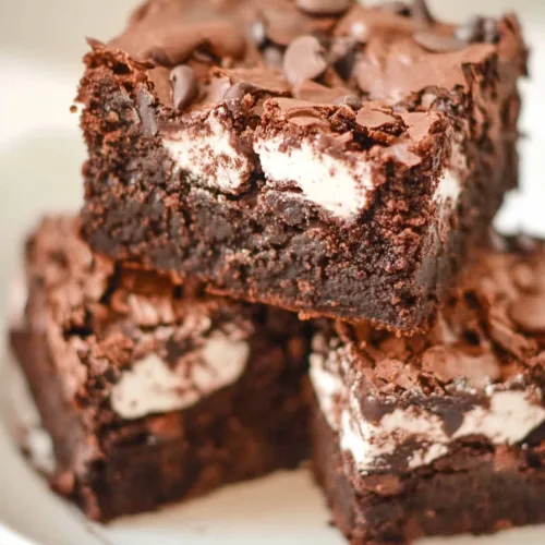 Three indulgent brownies layered neatly, highlighting dark chocolate and white swirls