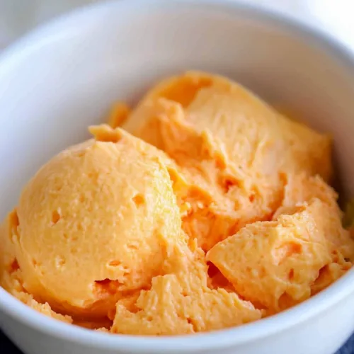 Scoops of creamy orange salad served in a white bowl.