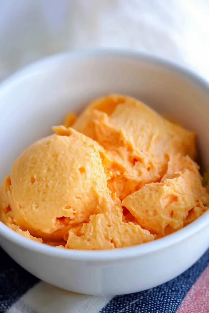 Scoops of creamy orange salad served in a white bowl.