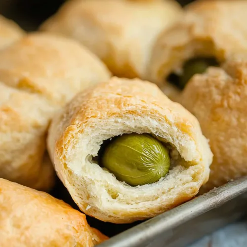 Close-up of golden-brown rolls with visible pickle ends.