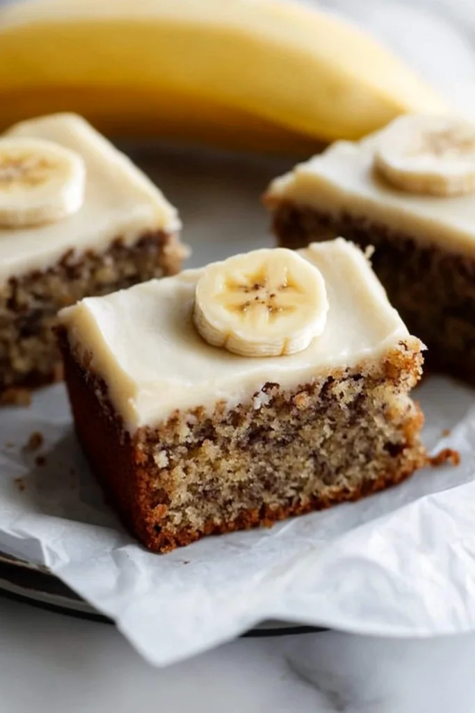 Layered cake highlighting frosting and banana topping.