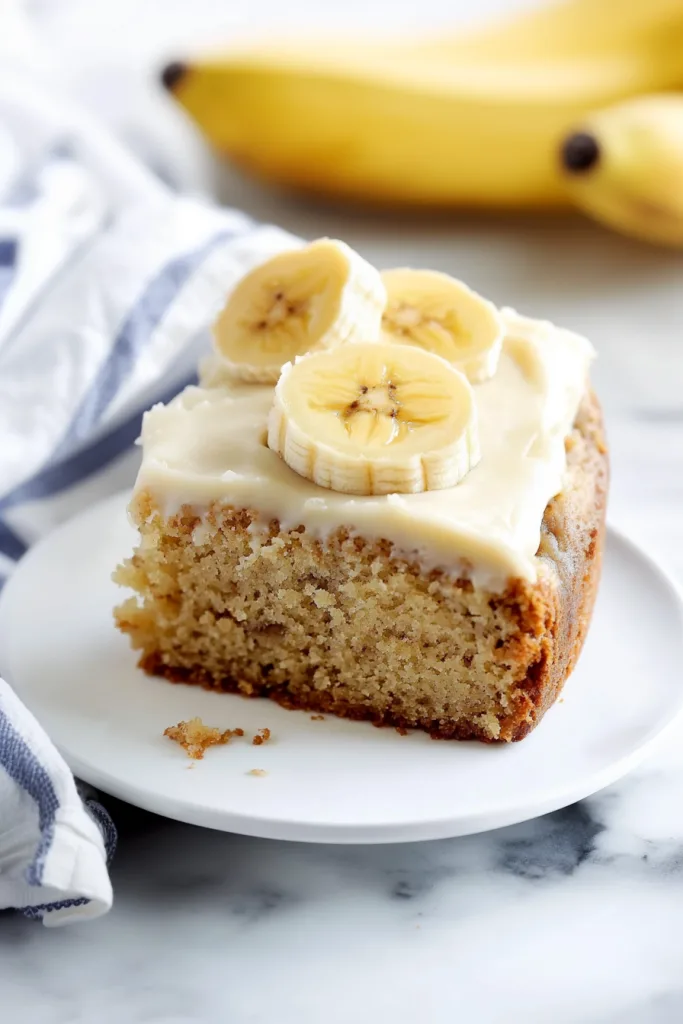 Banana Cake Recipe served with sliced bananas on top.