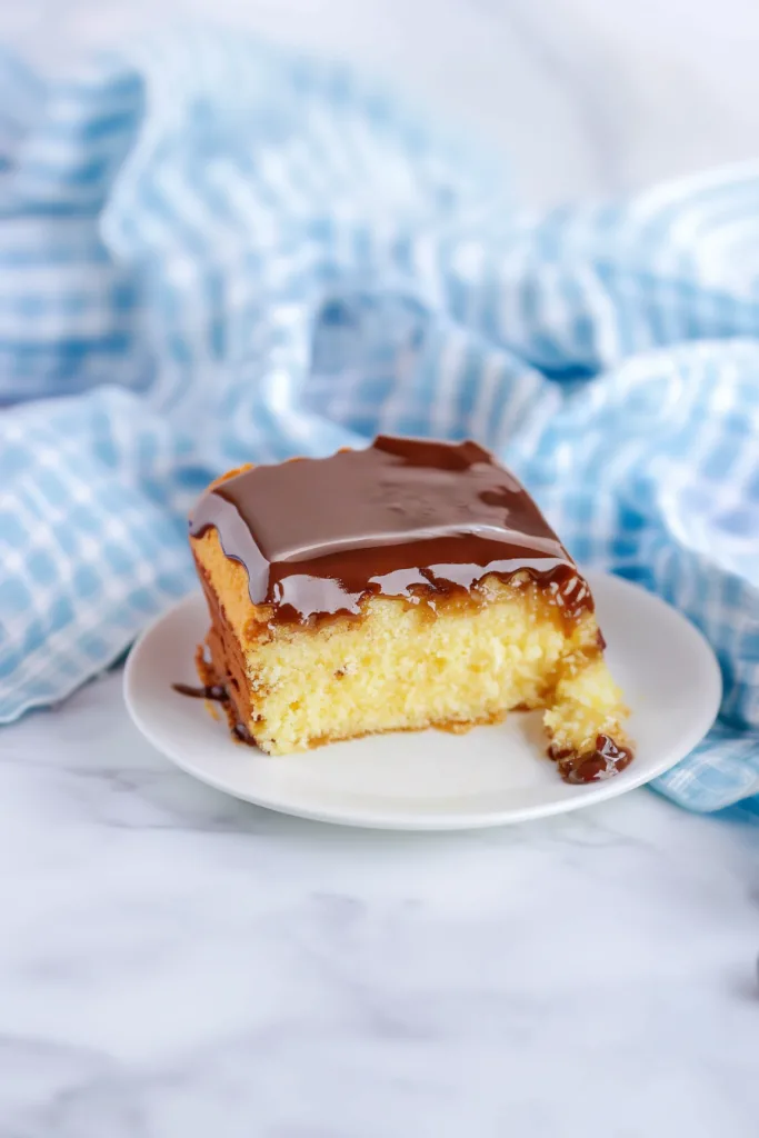 Piece of frosted cake served on a white plate.
