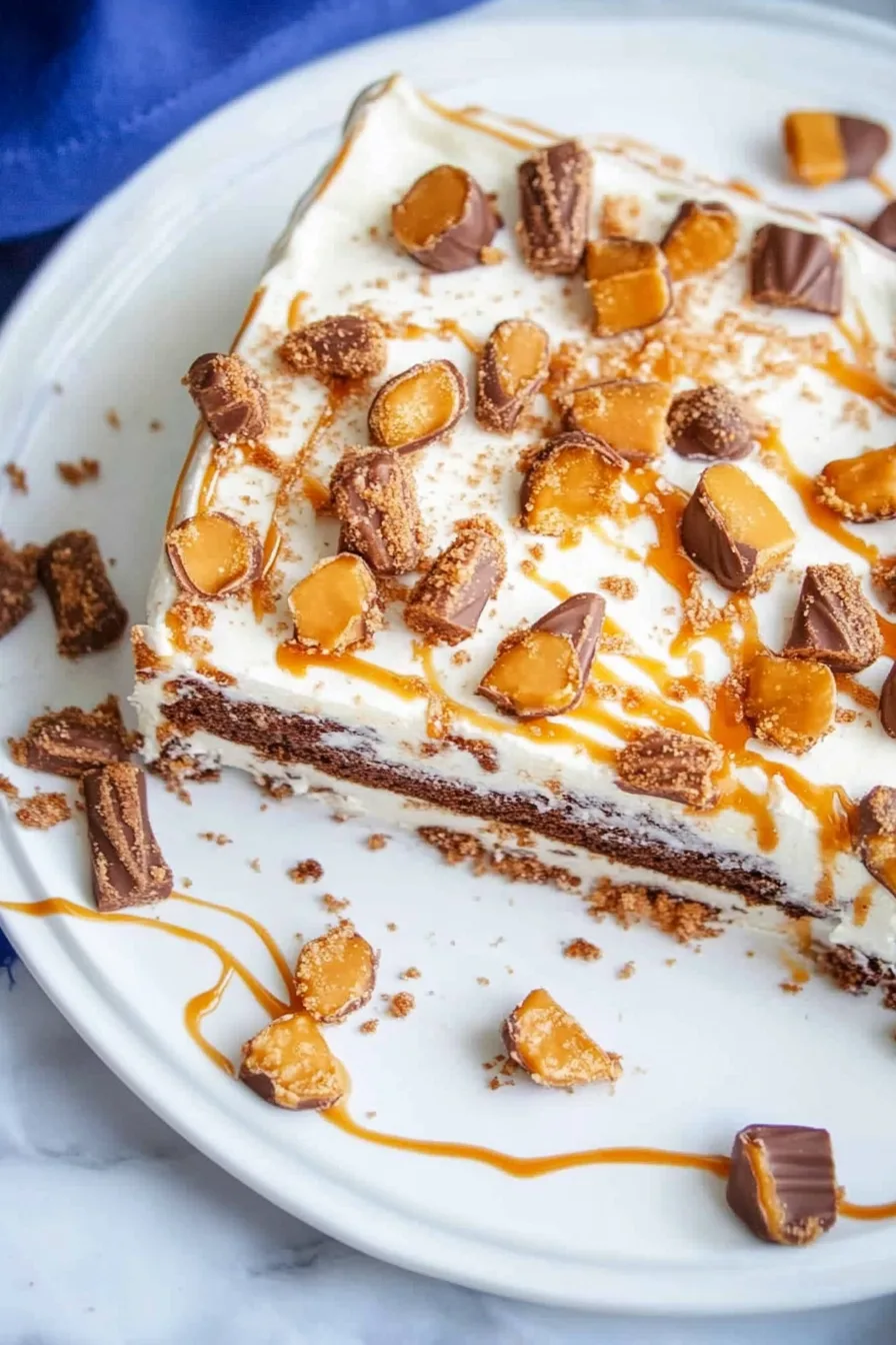 Cake with crumb-coated edges, rich frosting, and a generous layer of chopped caramel-chocolate bars.