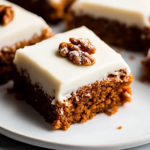Final shot of dense carrot cake with smooth frosting and pecan halves.