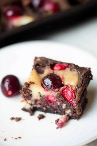 Overhead view of cheesecake brownies, garnished with whole cherries for a vibrant finish.