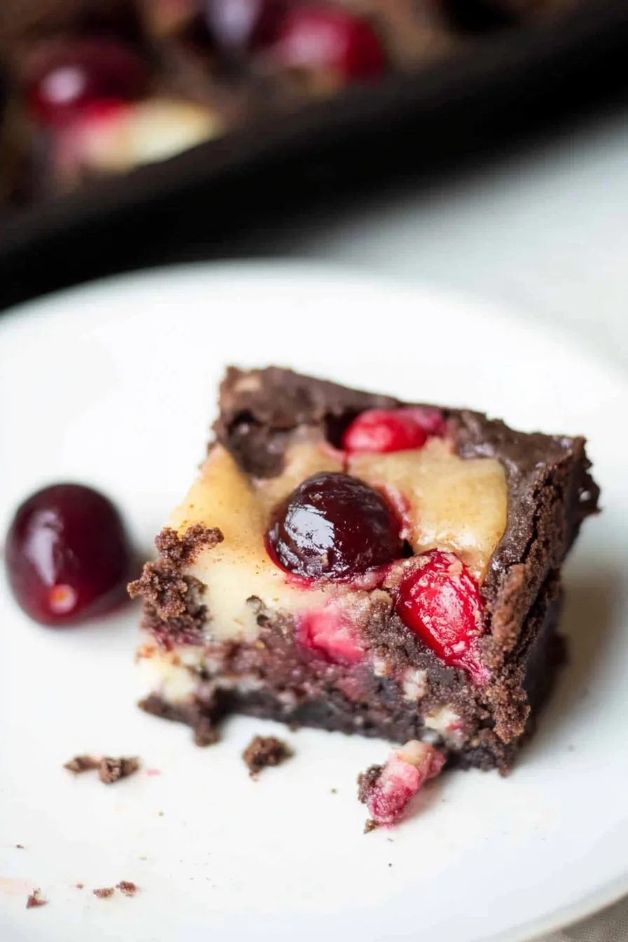 Overhead view of cheesecake brownies, garnished with whole cherries for a vibrant finish.