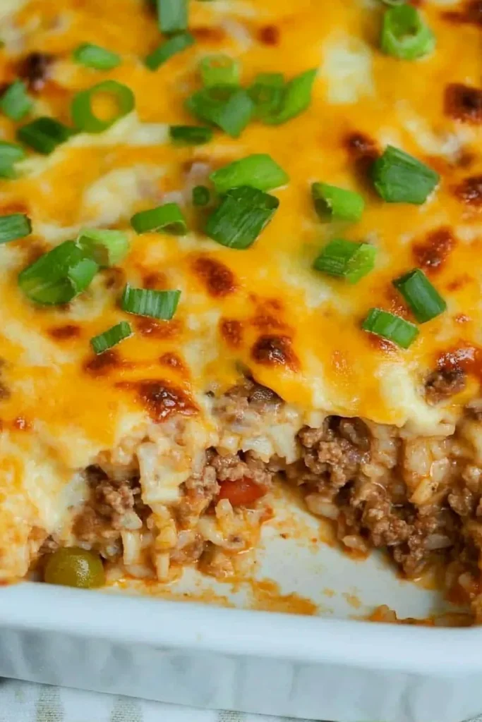 Close-up of cheesy rice and ground beef casserole, topped with fresh chopped scallions.