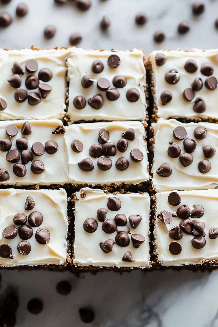 Neatly arranged dessert bars with smooth frosting and scattered chocolate chips.