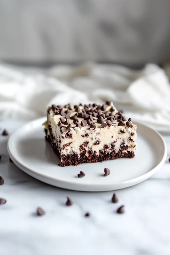 Square slice of layered dessert with creamy filling and scattered chocolate chips.