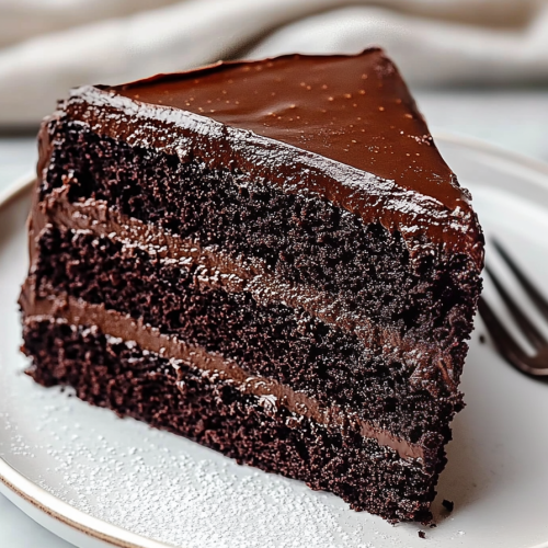 Chocolate Fudge Cake served with fork and sugar garnish.
