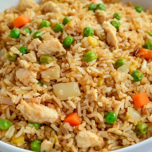 Bowl of fried rice with golden grains and vibrant vegetable mix.