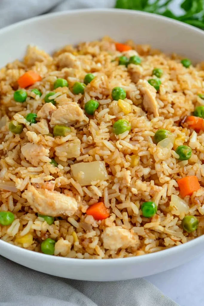 Bowl of fried rice with golden grains and vibrant vegetable mix.