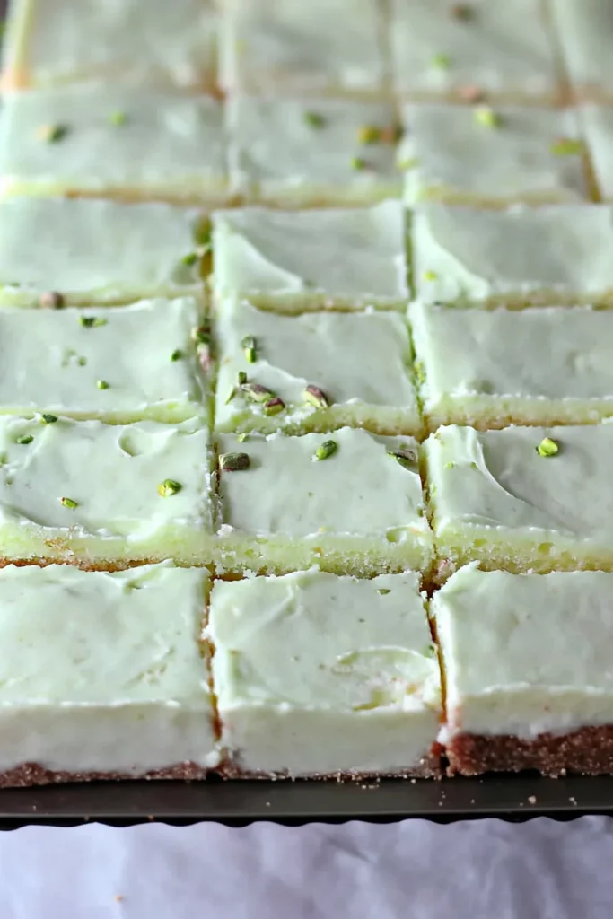 Serving tray with multiple slices of pistachio cake, highlighting smooth frosting texture.