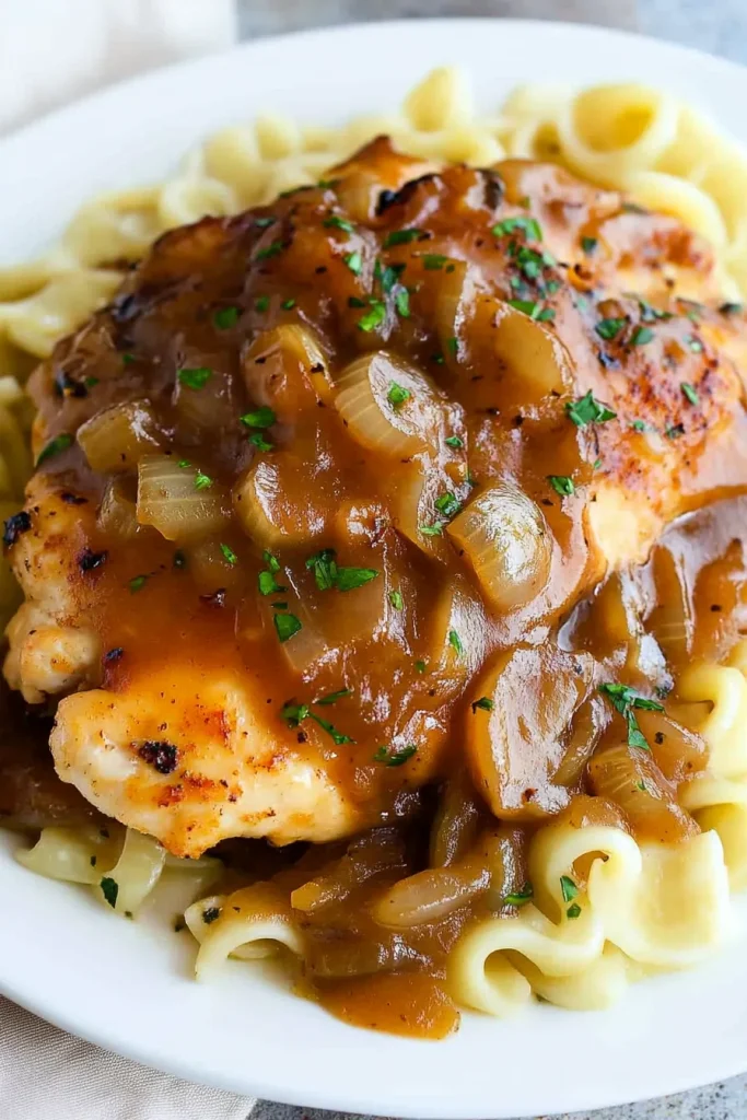 Close-up of tender chicken pieces smothered in mushroom and onion sauce.