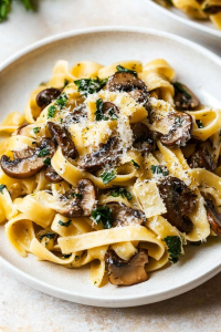 Fresh pasta served on a plate, garnished with parsley and Parmesan.