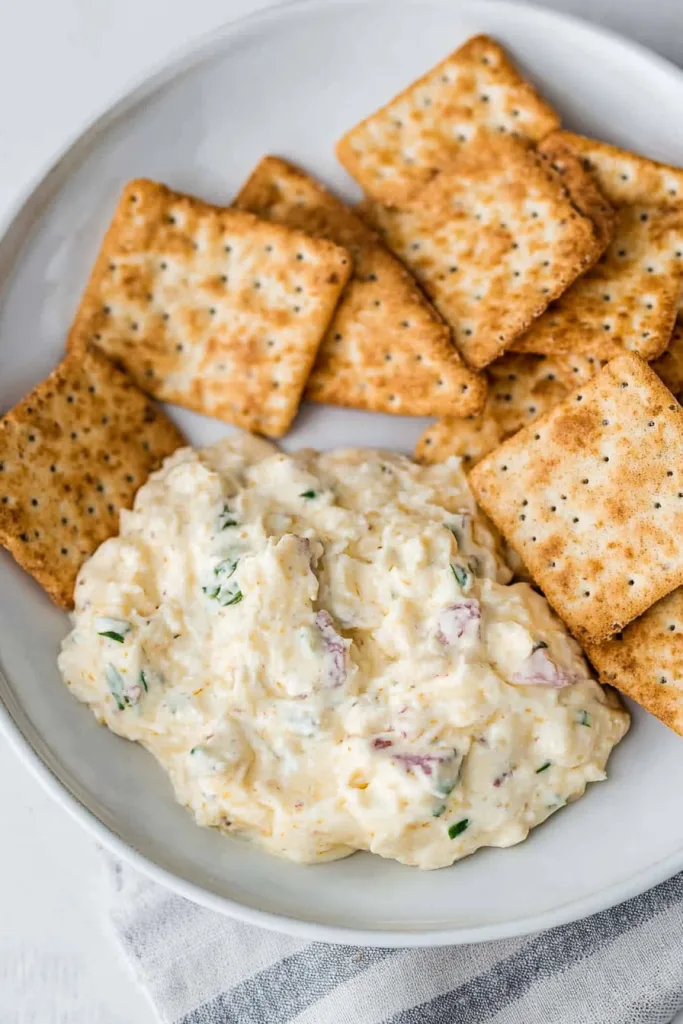 Golden crackers paired with a creamy, herb-speckled dip for entertaining.