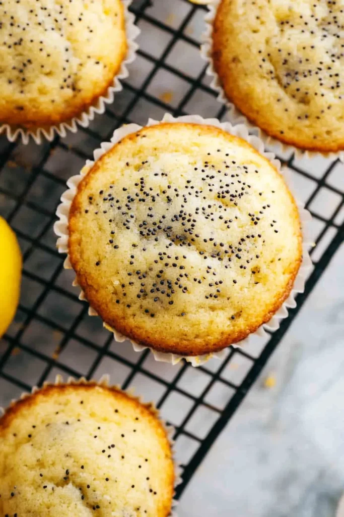 Freshly baked muffins cooling on a black rack with citrus garnish
