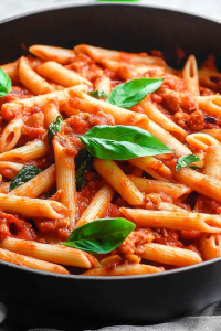 Warm pasta plated simply, showcasing glossy tomato sauce and melted cheese accents.