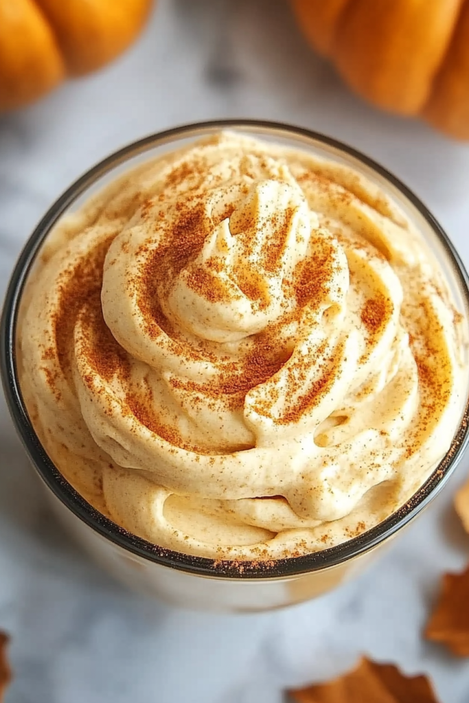 Close‑up of creamy whipped topping with soft swirls and a peak in the center.