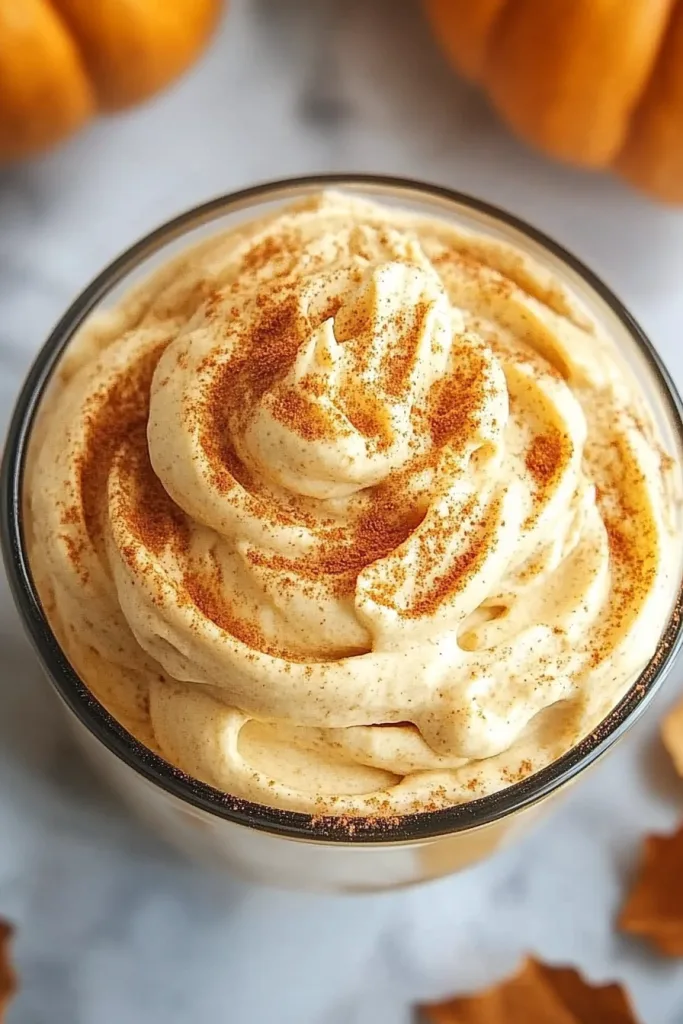 Close‑up of creamy whipped topping with soft swirls and a peak in the center.