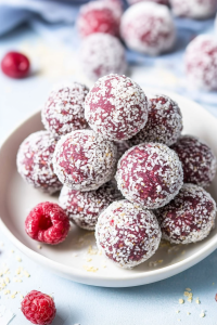 Final plated snack featuring coconut-covered balls and fresh berries for garnish.