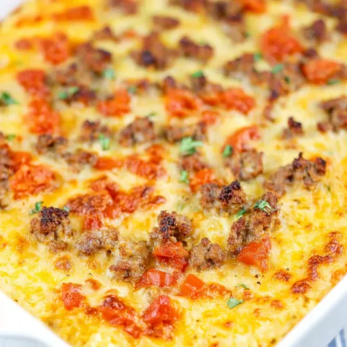 Rectangular dish of cheesy casserole resting on a patterned cloth.