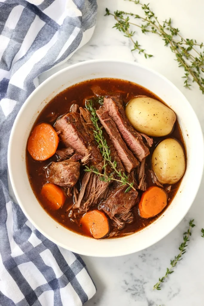 Close-up of pot roast garnished with fresh thyme sprigs.