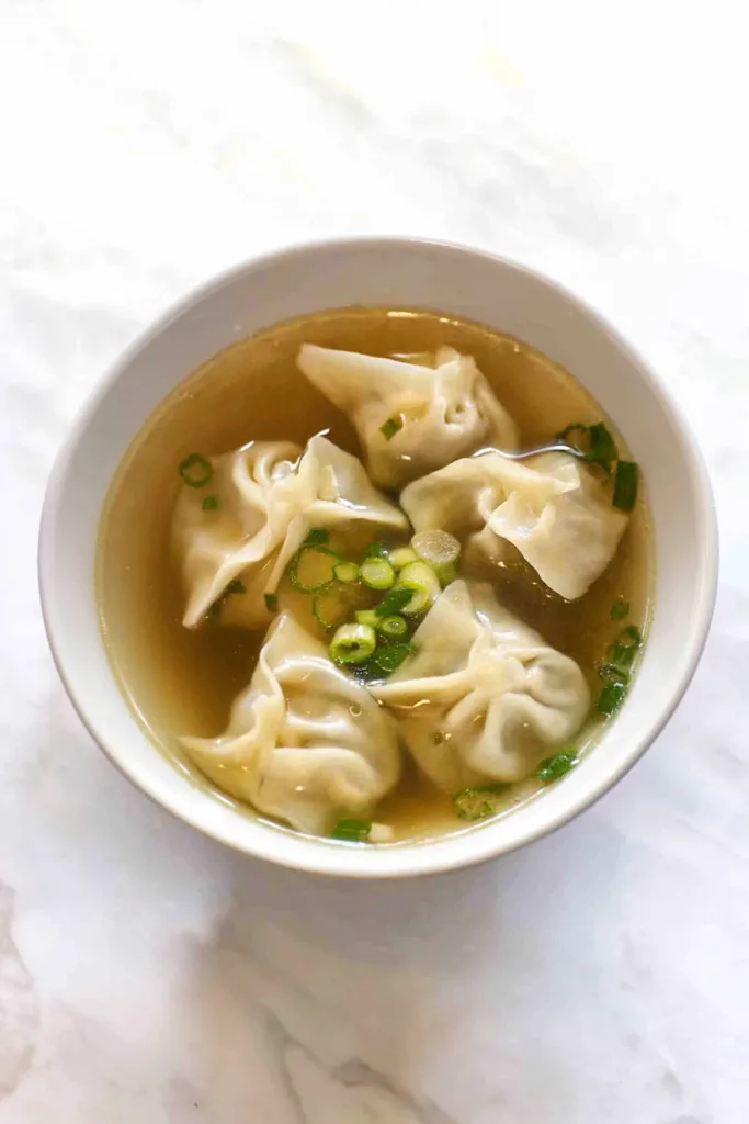 Warm soup highlighting translucent wrappers and savory broth.