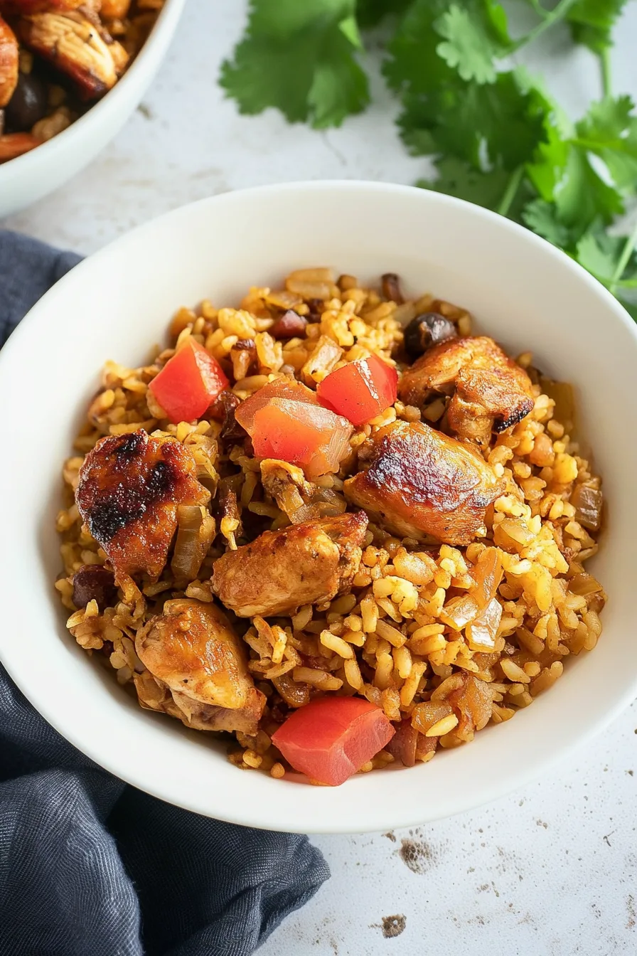 A vibrant rice dish with charred chicken, red peppers, and cilantro on top.