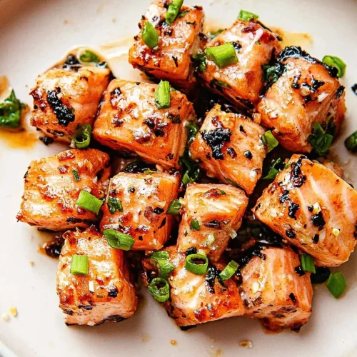 Appetizing salmon cubes arranged neatly with chopped herbs on top.