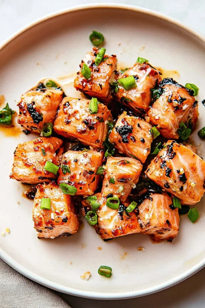 Appetizing salmon cubes arranged neatly with chopped herbs on top.