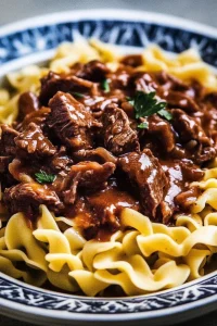 Comfort food scene featuring egg noodles coated in savory beef sauce.
